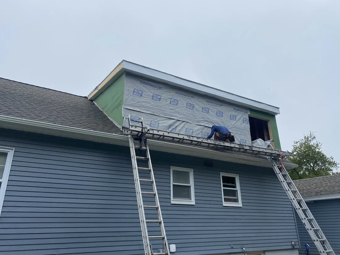 Siding and roof work in progress with ladders against the house