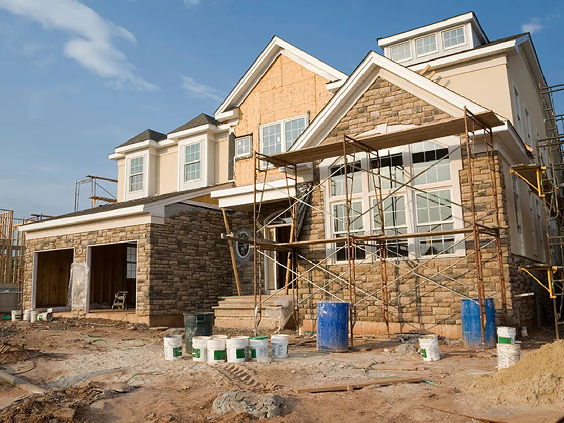 New construction house with scaffolding and stone exterior underway